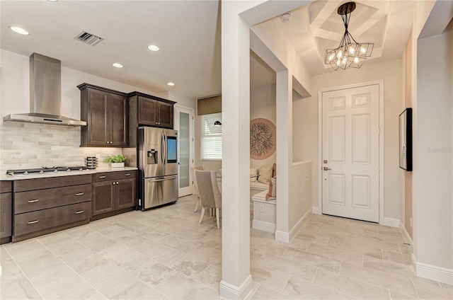 kitchen featuring hanging light fixtures, stainless steel appliances, backsplash, dark brown cabinets, and wall chimney exhaust hood