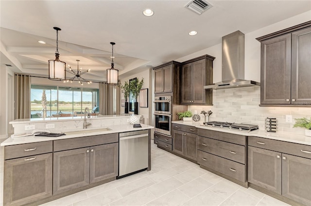 kitchen featuring appliances with stainless steel finishes, sink, wall chimney exhaust hood, hanging light fixtures, and dark brown cabinets