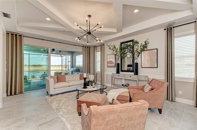 living room with a tray ceiling, light tile patterned floors, and an inviting chandelier