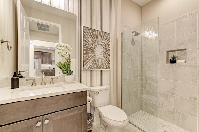 bathroom with a tile shower, vanity, and toilet