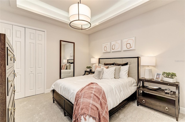 carpeted bedroom with a tray ceiling and a closet