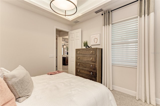 carpeted bedroom with a tray ceiling