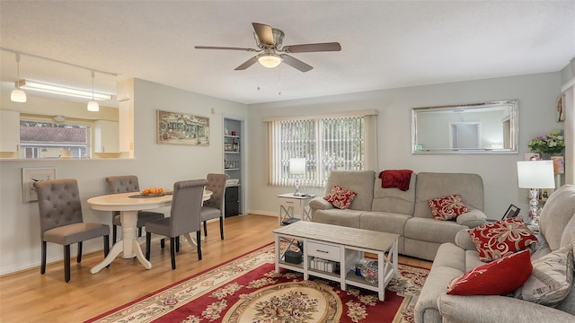 living room featuring a wealth of natural light, ceiling fan, baseboards, and wood finished floors