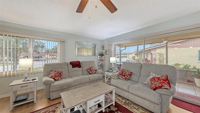 living area with light wood-style flooring, a ceiling fan, and a textured ceiling