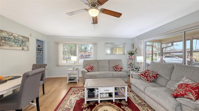 living room with a ceiling fan, light wood-style flooring, and baseboards