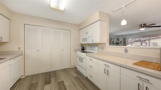 kitchen with a textured ceiling, white appliances, dark wood-style flooring, white cabinets, and light countertops