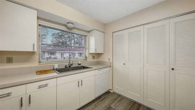 kitchen featuring dark wood-style flooring, light countertops, white cabinetry, white dishwasher, and a sink