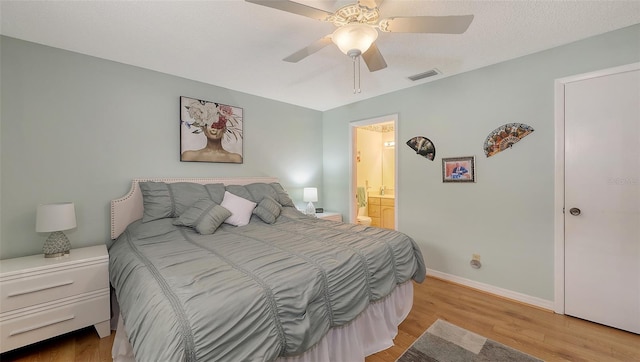 bedroom featuring light wood-type flooring, connected bathroom, visible vents, and baseboards