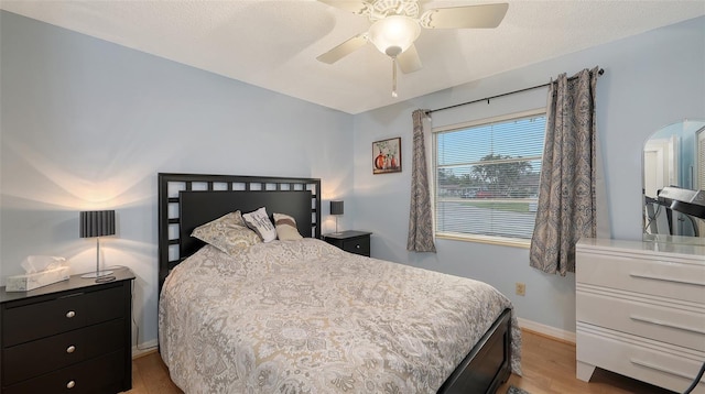 bedroom with light wood finished floors, baseboards, and a ceiling fan