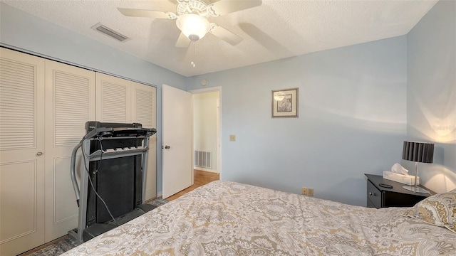 bedroom with a textured ceiling, a closet, visible vents, and a ceiling fan