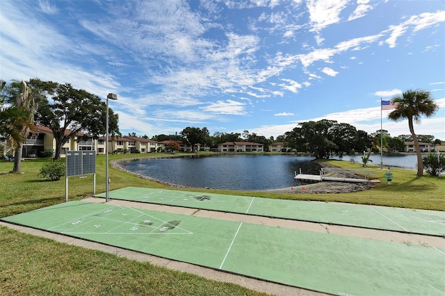 view of property's community featuring a water view, a lawn, and shuffleboard