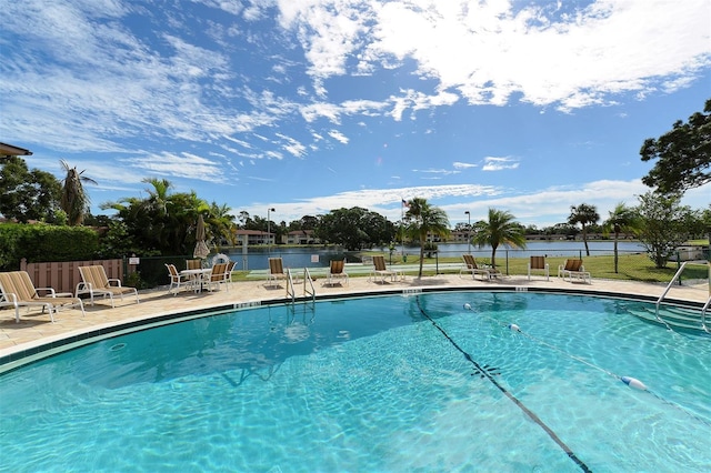 community pool with a water view, fence, and a patio