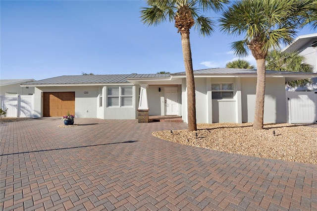 view of front of home featuring a garage, decorative driveway, metal roof, and stucco siding