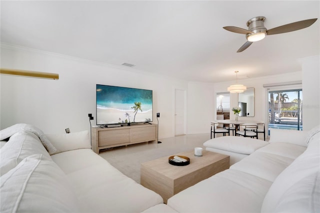 living room with light carpet, ceiling fan, visible vents, and crown molding