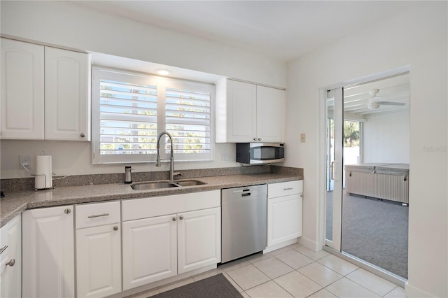 kitchen with dark countertops, a wealth of natural light, appliances with stainless steel finishes, white cabinetry, and a sink