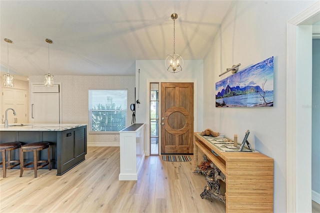 entrance foyer with a chandelier, light wood-style flooring, and baseboards