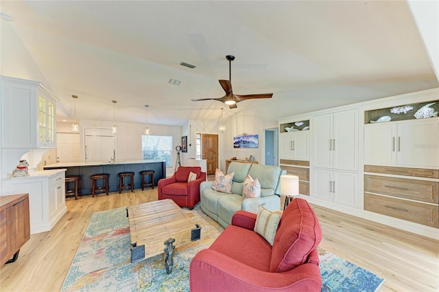 living room with lofted ceiling, light wood-style flooring, a ceiling fan, and visible vents