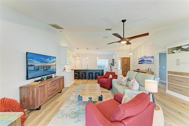 living area featuring light wood-type flooring, lofted ceiling, and visible vents