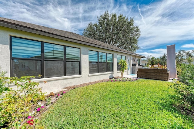 rear view of property featuring a lawn and stucco siding