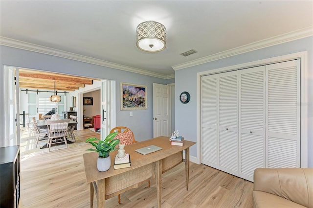 home office featuring baseboards, visible vents, light wood finished floors, and ornamental molding