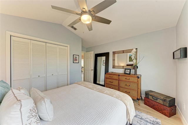 bedroom with visible vents, light wood finished floors, baseboards, lofted ceiling, and a closet