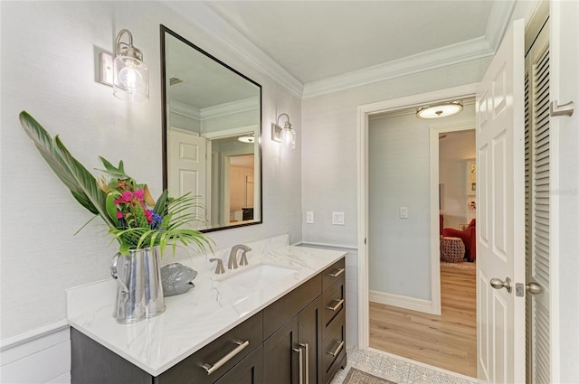 bathroom with vanity, wood finished floors, baseboards, and ornamental molding