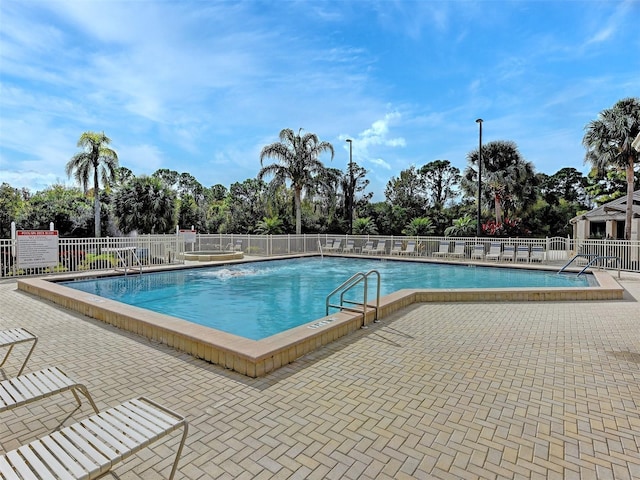 community pool with a patio area and fence