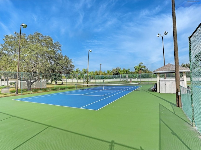 view of tennis court featuring community basketball court and fence