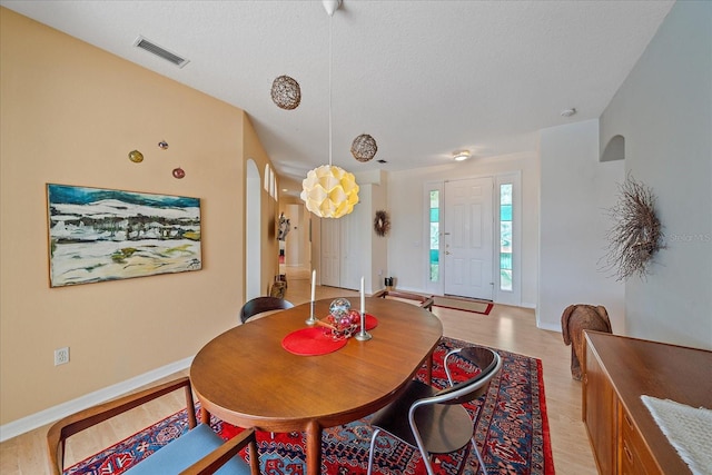 dining space with a textured ceiling and light hardwood / wood-style flooring