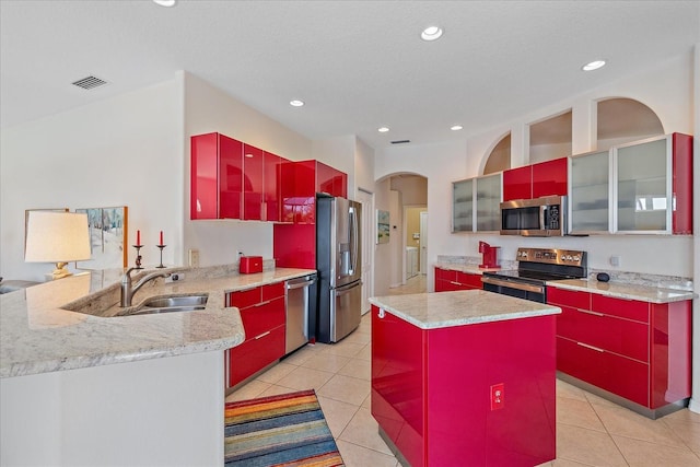 kitchen with light tile patterned flooring, appliances with stainless steel finishes, a kitchen island, and kitchen peninsula