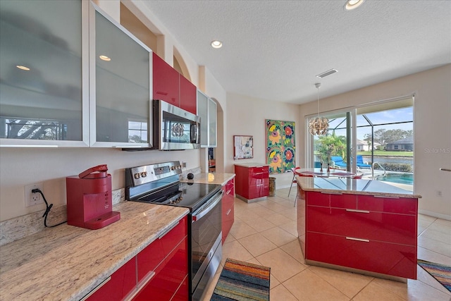 kitchen with light tile patterned flooring, a center island, appliances with stainless steel finishes, and a textured ceiling