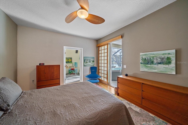 bedroom featuring hardwood / wood-style flooring, ceiling fan, access to exterior, and a textured ceiling