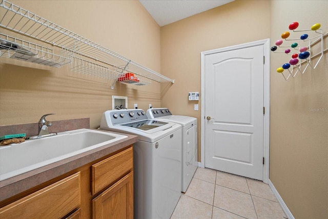 clothes washing area featuring sink, light tile patterned floors, and washer and dryer