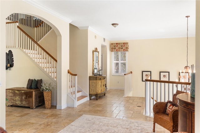 foyer featuring a chandelier, ornamental molding, stone tile flooring, and baseboards