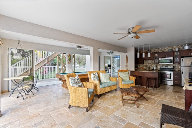 living area with ceiling fan, pool table, and stone tile flooring