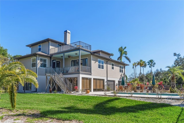 back of house with a lawn, stairway, a ceiling fan, fence, and a balcony