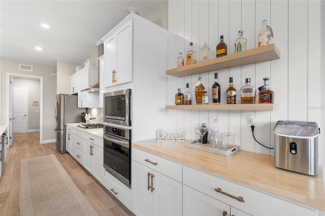 kitchen featuring white cabinetry, light hardwood / wood-style floors, appliances with stainless steel finishes, and decorative backsplash