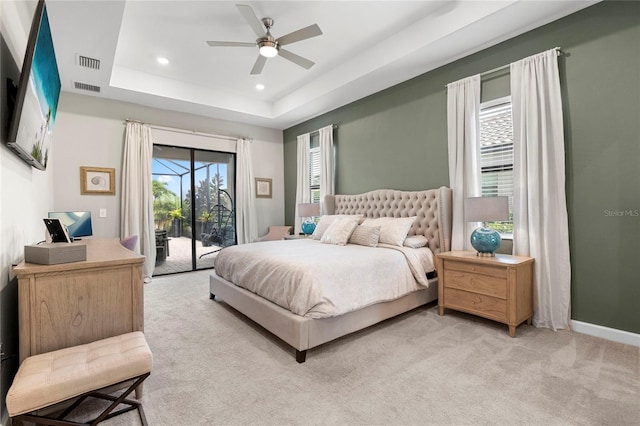 bedroom featuring light carpet, ceiling fan, a tray ceiling, and access to outside