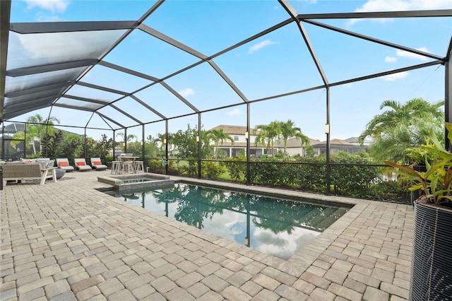 view of pool with a patio area, outdoor lounge area, an in ground hot tub, and glass enclosure