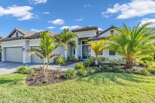 view of front of property with a garage, a front lawn, decorative driveway, and stucco siding