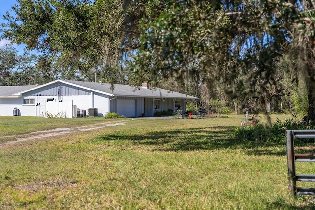 view of front facade featuring a garage, board and batten siding, a front yard, and cooling unit