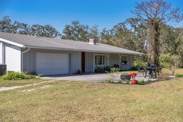 single story home featuring an attached garage, a front lawn, board and batten siding, and concrete driveway