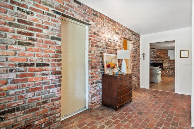 hall with brick wall, brick floor, and baseboards