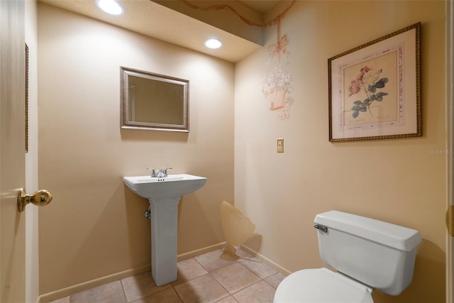 half bath with recessed lighting, toilet, a sink, tile patterned flooring, and baseboards