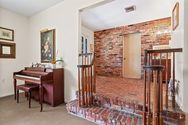 living area with brick wall, baseboards, and visible vents