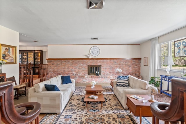 living room featuring brick wall, a fireplace, and visible vents