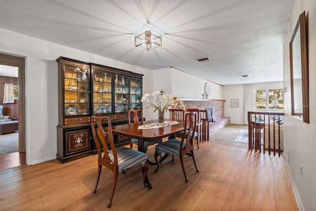 dining space featuring light wood-style floors, visible vents, and a fireplace