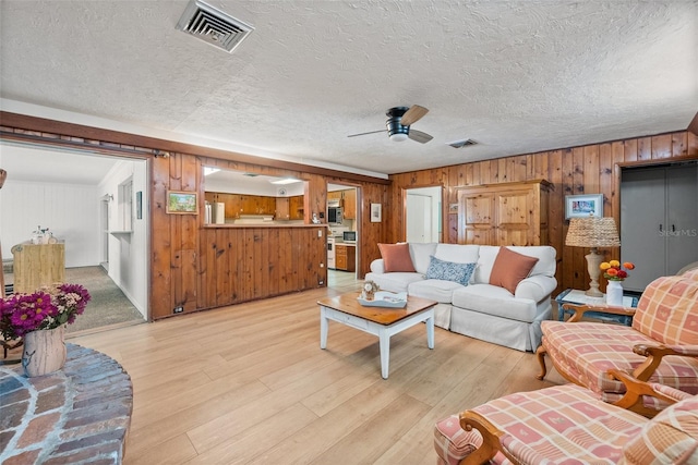 living area with light wood-style floors, visible vents, and a textured ceiling