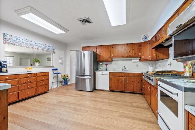 kitchen with brown cabinets, stainless steel appliances, light countertops, visible vents, and light wood-style floors