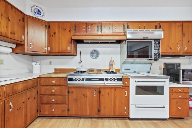 kitchen with stainless steel appliances, brown cabinetry, light countertops, and light wood finished floors